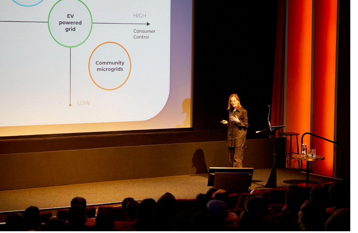 Evi presenting on the main stage at Future of Utilities Amsterdam, with an energy transition slide visible behind her